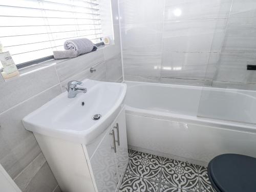 a white bathroom with a sink and a bath tub at Keekle Terrace in Cleator Moor