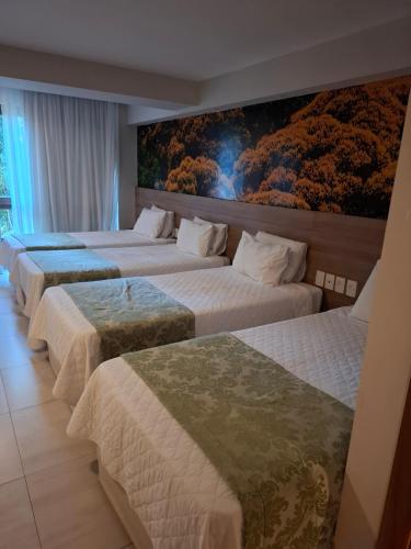 Vista Azul Apart - Vista Mata Atlântica في بيدرا أزول: صف من أربعة أسرة في غرفة فندق