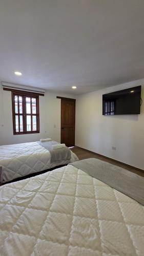 a large bedroom with two beds and a flat screen tv at Escencia raquireña in Ráquira
