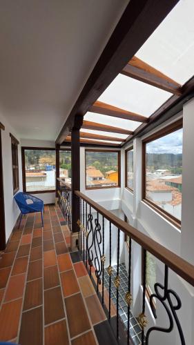 a balcony with a blue chair and windows at Escencia raquireña in Ráquira