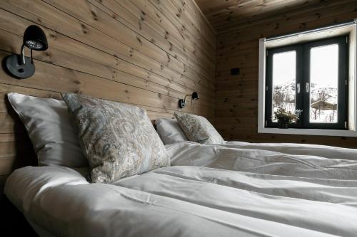 a bedroom with a white bed in a wooden wall at Skigaarden in Hemsedal