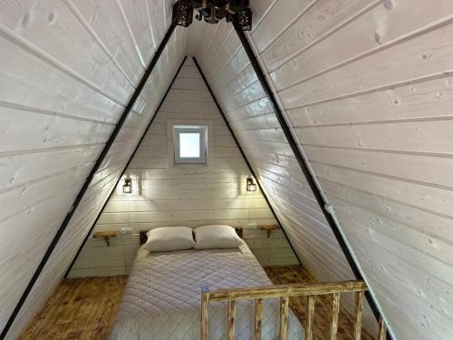 Una cama en una habitación pequeña en una casa triangular. en Орхідея LUXE 3, en Synevyrsʼka Polyana
