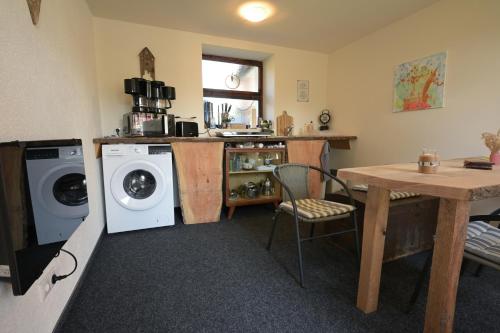 a kitchen with a washing machine and a table at Zittau - Ferienwohnung Frieda mit Camping Familien, und Biker Hütten am Zittauer Gebirge in Zittau