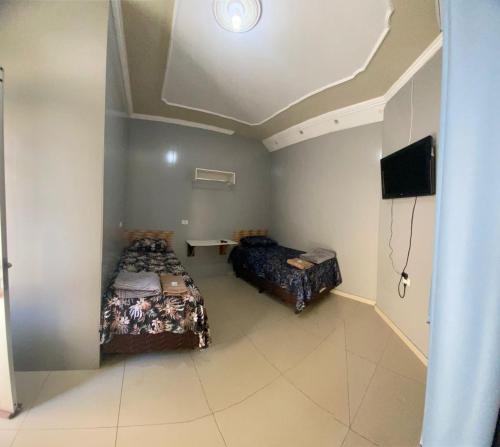 a room with two beds and a flat screen tv at Hotel Ideal in Ribas do Rio Pardo