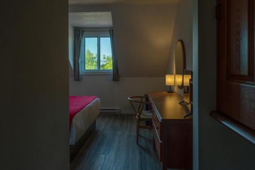 a bedroom with a bed and a desk and a window at Hotel Cowansville in Cowansville