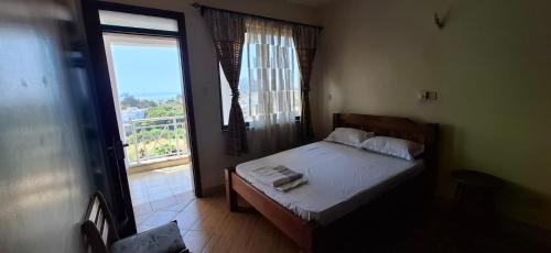a small bedroom with a bed and a large window at Zamia Heights Apartments in Gatunga