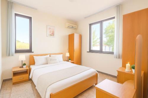 a bedroom with a large bed and two windows at Velika Garden Villas 1 bedroom apartment, Lozenets in Lozenets