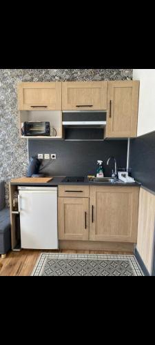 a kitchen with wooden cabinets and a white refrigerator at Duplex plage de brehec in Plouézec