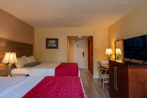 a hotel room with two beds and a flat screen tv at Hotel Cowansville in Cowansville