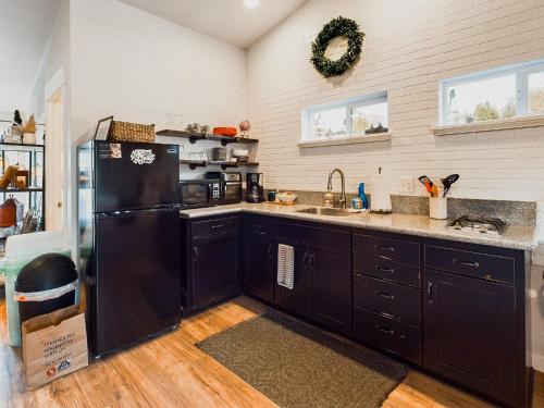 a kitchen with black cabinets and a black refrigerator at PNW Scenic Loft with Kitchenette in Philomath