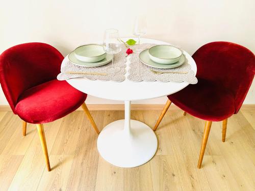 une table avec deux chaises rouges et une table blanche avec une assiette dans l'établissement cozy isola garden, à Milan