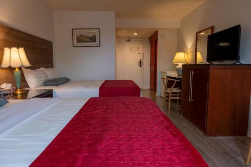 a hotel room with two beds and a flat screen tv at Hotel Cowansville in Cowansville