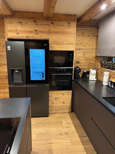 a kitchen with black appliances and wooden walls at Leos Chalet in Valdaora di Sopra
