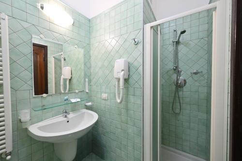 a green tiled bathroom with a sink and a shower at Av Isola Verde Hotel Thermal Spa in Ischia