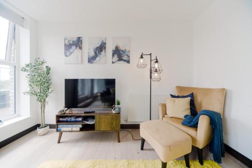 Una sala de estar con una silla y un televisor. en Step Free -Fully Private -Equipped Kitchen- 2 Bed 2 bathroom Dartford London Flat Mins from Bluewater and Station with 500mb Wifi, en Dartford