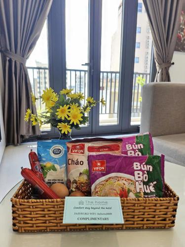 una cesta llena de comida y un jarrón de flores en The Home Hotel & Apartment, en Da Nang