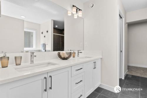 a white kitchen with a sink and a mirror at Luxurious Detached House with Private Garage, Lake View, Central AC & More in Airdrie