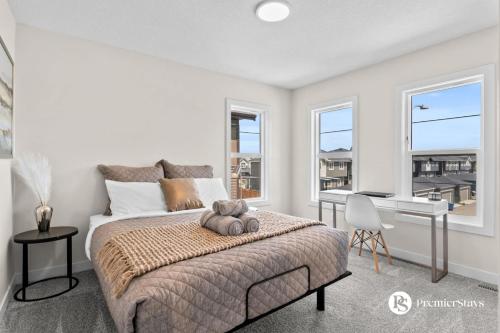 a bedroom with a bed and a desk and windows at Luxurious Detached House with Private Garage, Lake View, Central AC & More in Airdrie