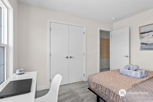 a white bedroom with a bed and a desk at Luxurious Detached House with Private Garage, Lake View, Central AC & More in Airdrie