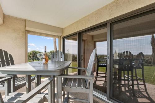 a table and chairs on a balcony with glass doors at Amelia Surf and Racquet Club Condo - Ocean View - 1st Floor - Pools - Tennis Courts - Sleeps 8 in Fernandina Beach