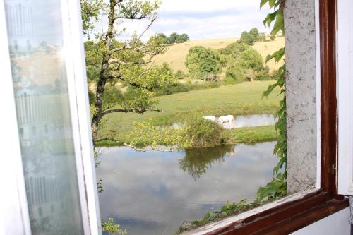an open window with a view of a lake at Le moulin de vaux in Nochizé
