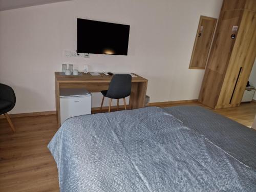 a bedroom with a bed and a desk with a television at Apartmani i sobe PARK in Apatin