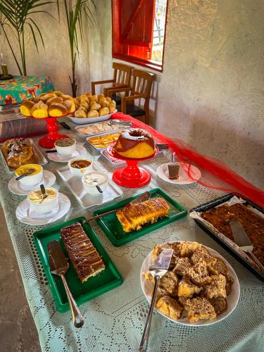 ein Tisch mit einem Buffet mit Speisen und Desserts in der Unterkunft Pousada da Janjana in Nova Iguaçu