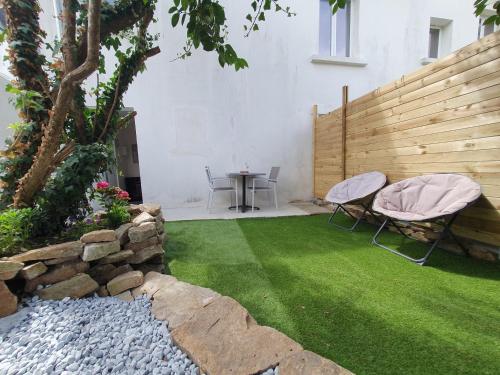 a backyard with a lawn with two chairs and a table at Apartment in Passage on GR34 in Concarneau