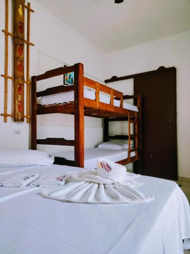 a bedroom with two bunk beds with white sheets at Pousada Aconchego Recanto Do Mar - São Sebastião - Caraguatatuba in São Sebastião