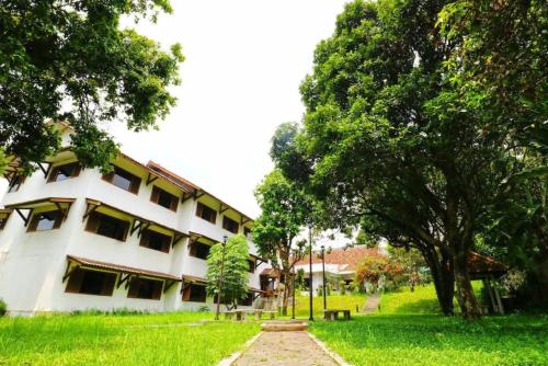 a white building with a tree in front of it at Graha Asri Hotel in Bandung