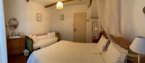 a bedroom with a white bed and a couch at Chez Providence Chambres et Table d'Hôtes in Cuxac-Cabardès