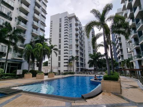 a large swimming pool with palm trees and buildings at Palm Tree Condos across NAIA3 by Beth in Manila