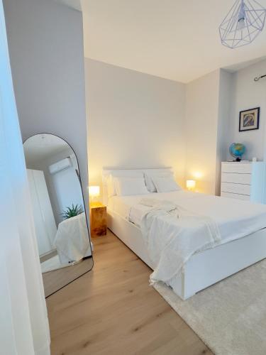a white bedroom with a large bed and a mirror at La Terrazza Sulla Valle in Sgurgola