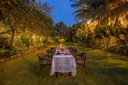 a table with a white table cloth and chairs in a yard at Coco Island Resort Ninh Binh in Ninh Binh