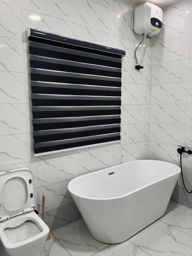 La salle de bains blanche est pourvue d'une baignoire et de toilettes. dans l'établissement Orchard Apartments Ile - Ife Osun State Nigeria, à Ile-Ife