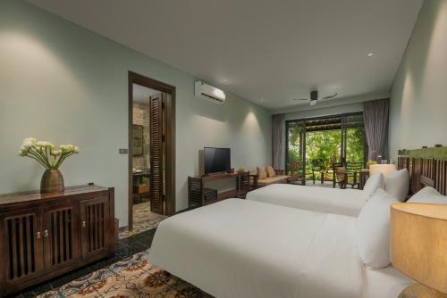 a bedroom with a white bed and a television at Coco Island Resort Ninh Binh in Ninh Binh