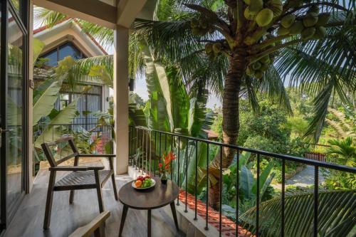 a balcony with a chair and a table and a palm tree at Coco Island Resort Ninh Binh in Ninh Binh