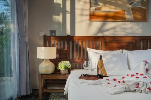 a bedroom with a bed with white sheets and wine glasses at Coco Island Resort Ninh Binh in Ninh Binh