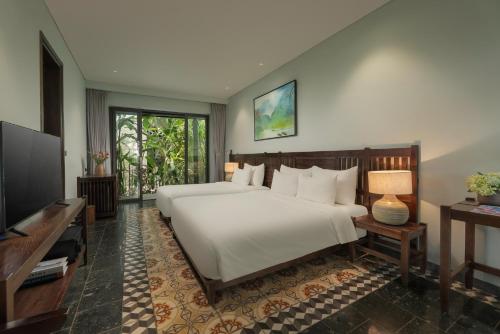 a bedroom with a large white bed and a television at Coco Island Resort Ninh Binh in Ninh Binh