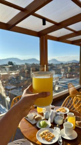 een persoon met een glas sinaasappelsap op een tafel bij Qasamarca Hotel Boutique in Cajamarca