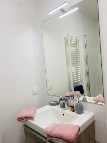 a bathroom with a sink with a mirror and pink towels at chambre avec salle de bain privée au cœur de La Défense in Nanterre
