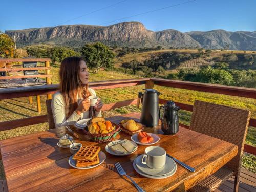 a woman sitting at a table with a plate of food at Pousada e Chalés Passaredo Canastra in São Roque de Minas