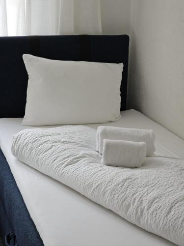 a white bed with two white towels on it at Habibi Apartment - Aare Jungfrau AG in Wilderswil