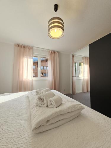 a bedroom with a white bed with towels on it at Habibi Apartment - Aare Jungfrau AG in Wilderswil