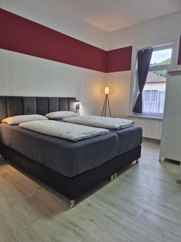 a bedroom with two beds and a red wall at Pension Kreihe im Harz in Bad Lauterberg