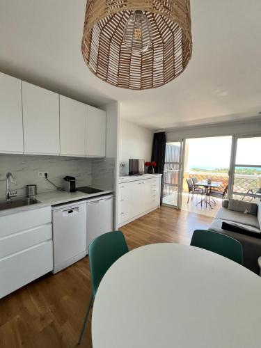 Una cocina con gabinetes blancos y una mesa con sillas. en Cap Esterel - Charmant T2 climatisé vue mer 4/5 pers - Piscine - Parking, en Agay - Saint Raphael