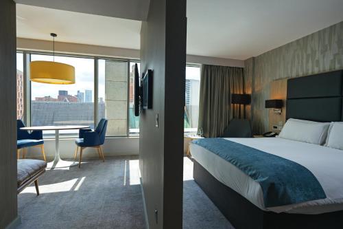a hotel room with a bed and a table with a desk at Holiday Inn Manchester - City Centre by IHG in Manchester