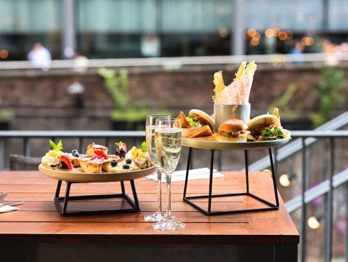 a table with two plates of food and a glass of wine at Holiday Inn Manchester - City Centre by IHG in Manchester