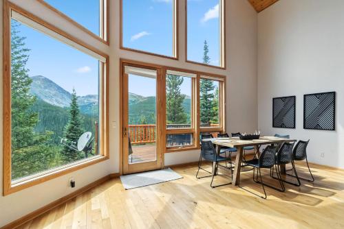 Un comedor con mesa y sillas y grandes ventanales. en Breckenridge Retreat Hot Tub and Mountain Vistas, en Breckenridge