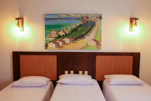 two beds in a room with a painting on the wall at Village Club in Pipa